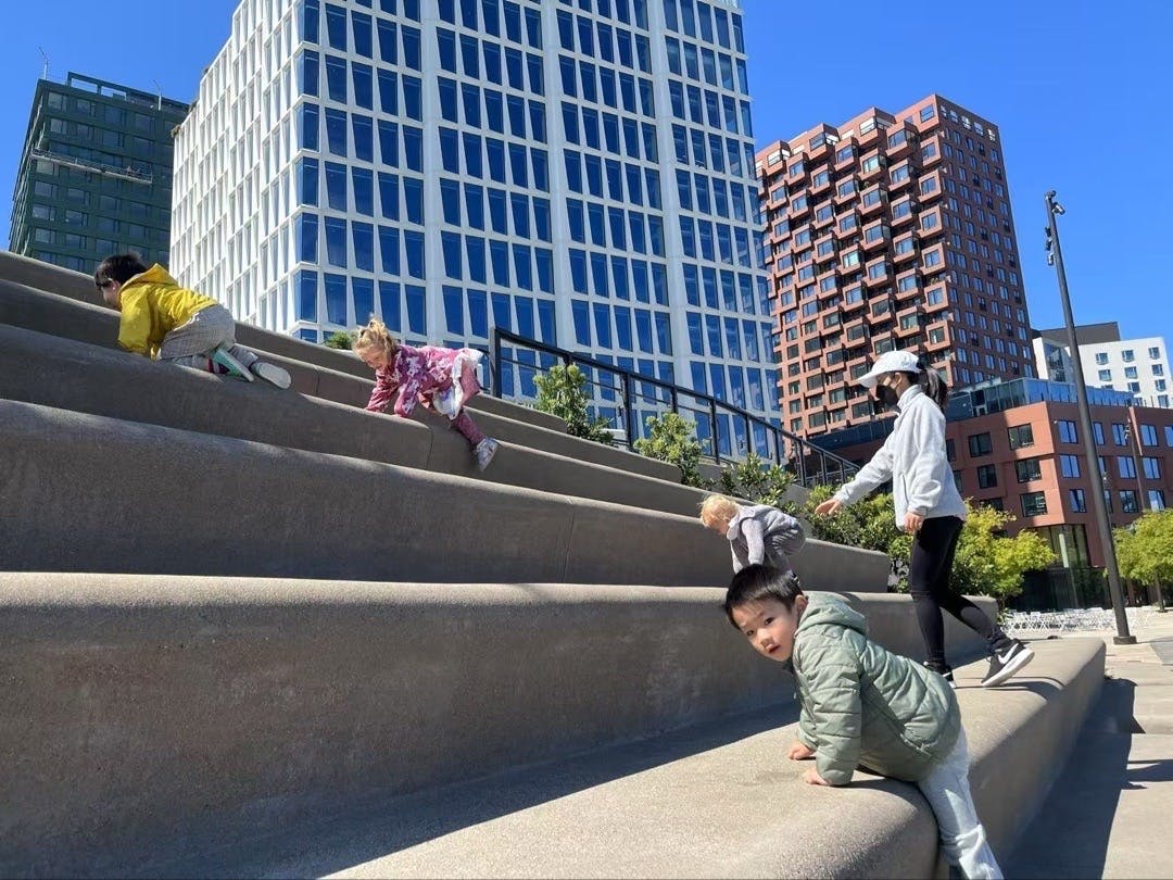 Children and a person climbing large outdoor steps