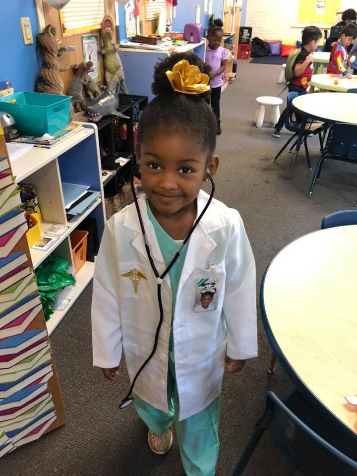 Child in a doctor's coat and stethoscope in a classroom