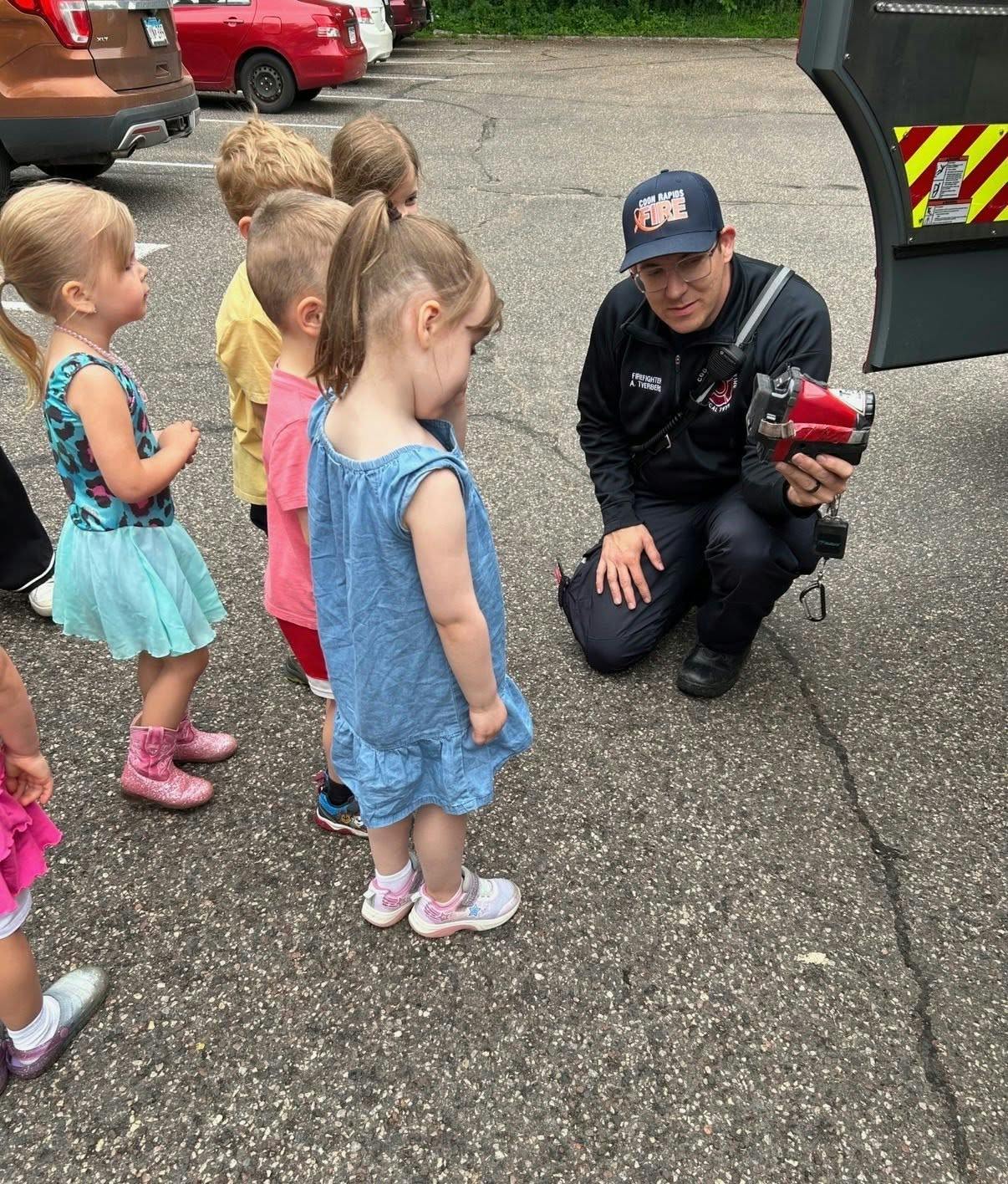 Firefighter showing equipment to a group of children outdoors