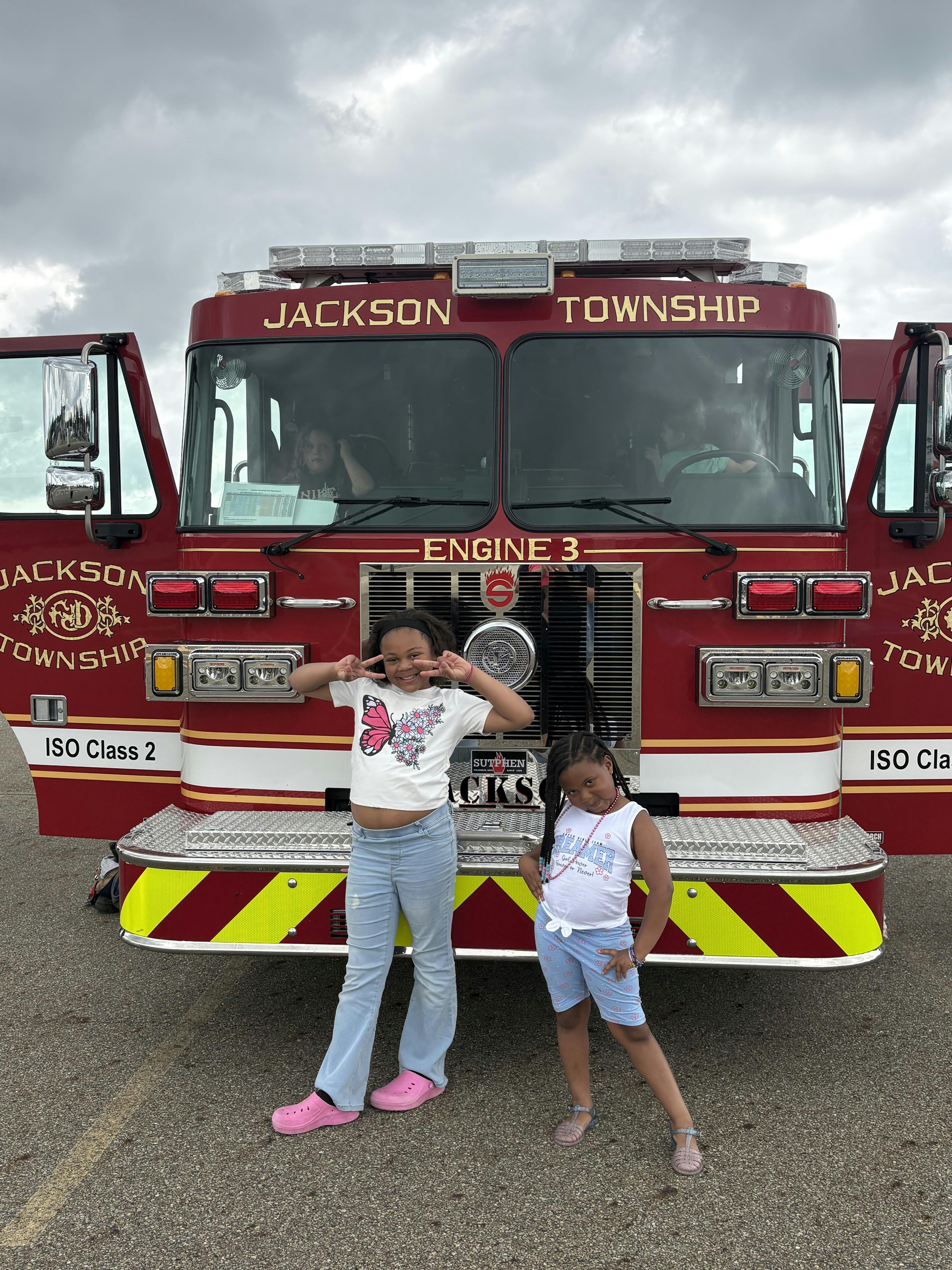 Two children standing in front of a Jackson Township fire engine