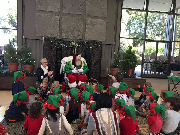 Person dressed as Santa Claus with children wearing elf hats