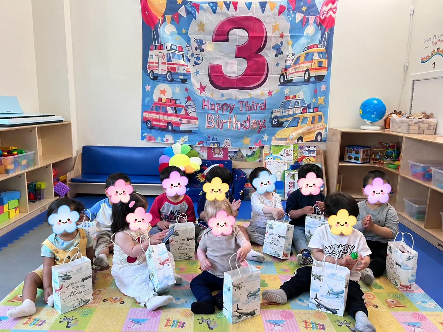 Children sitting on a colorful floor mat with party bags at a birthday celebration