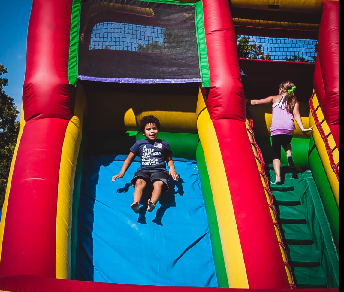 Child sliding down an inflatable slide, another child climbing up