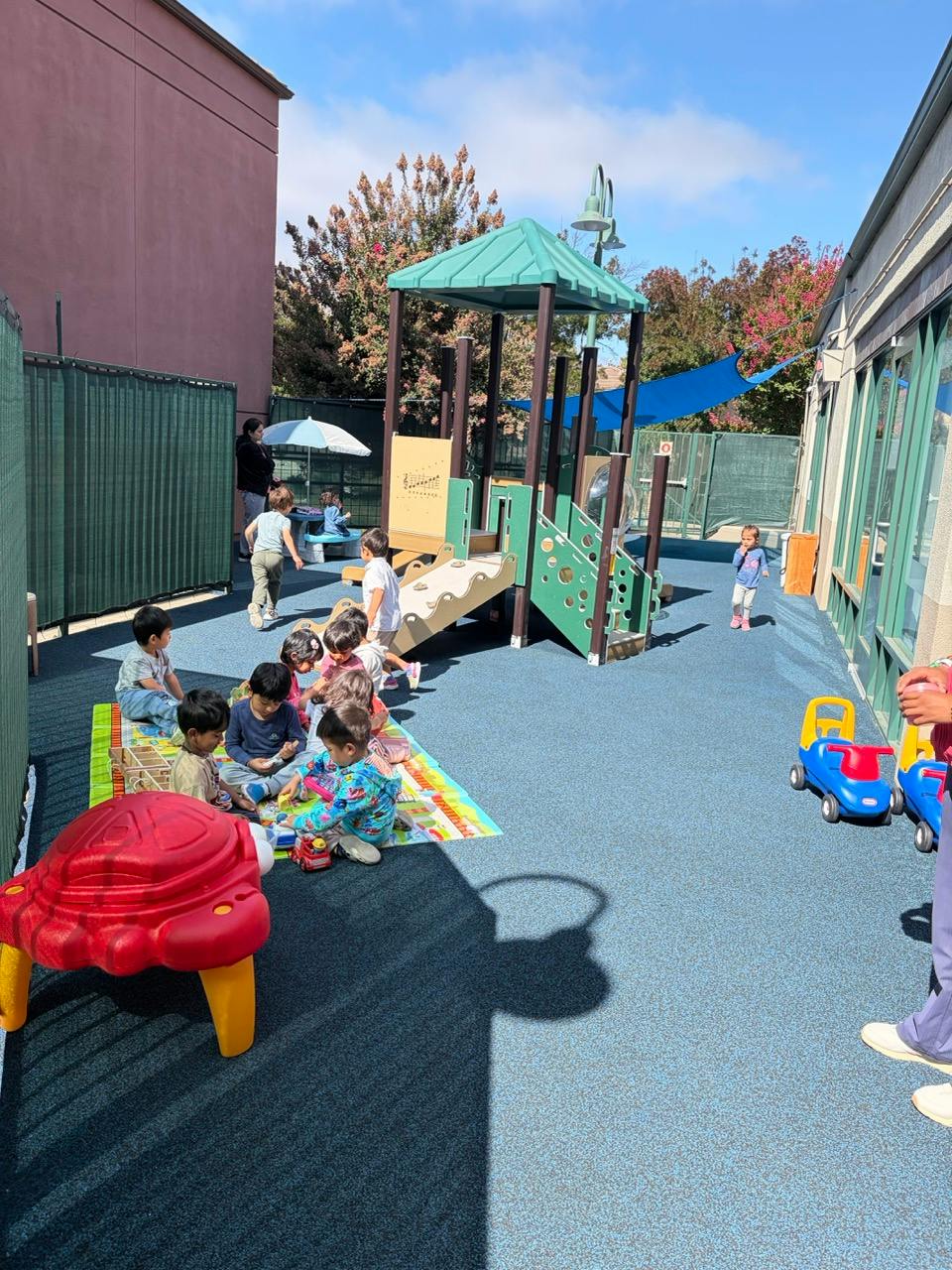 Group of children playing on a mat at an outdoor preschool playground
