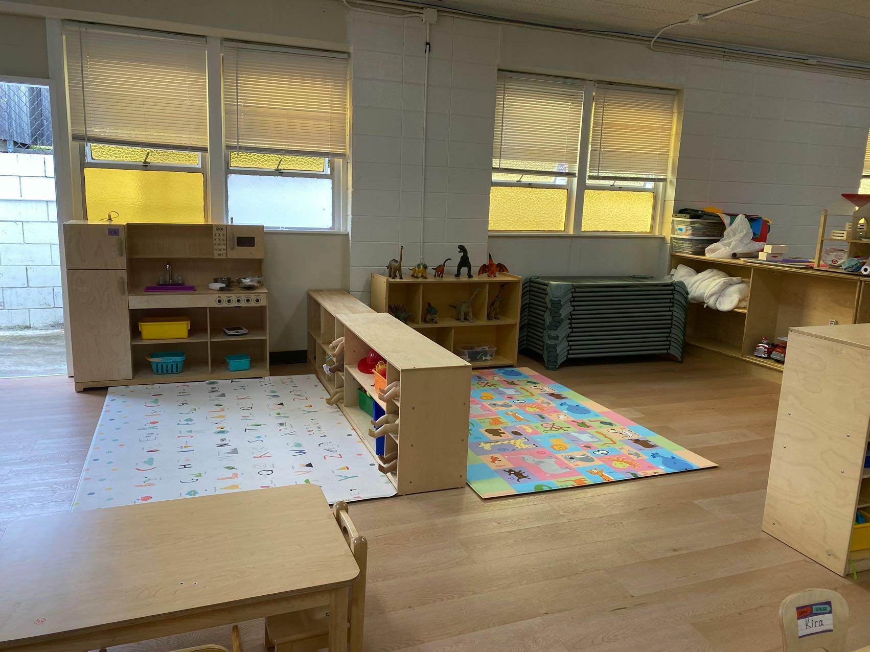 Classroom with play kitchen, shelves, and colorful rugs