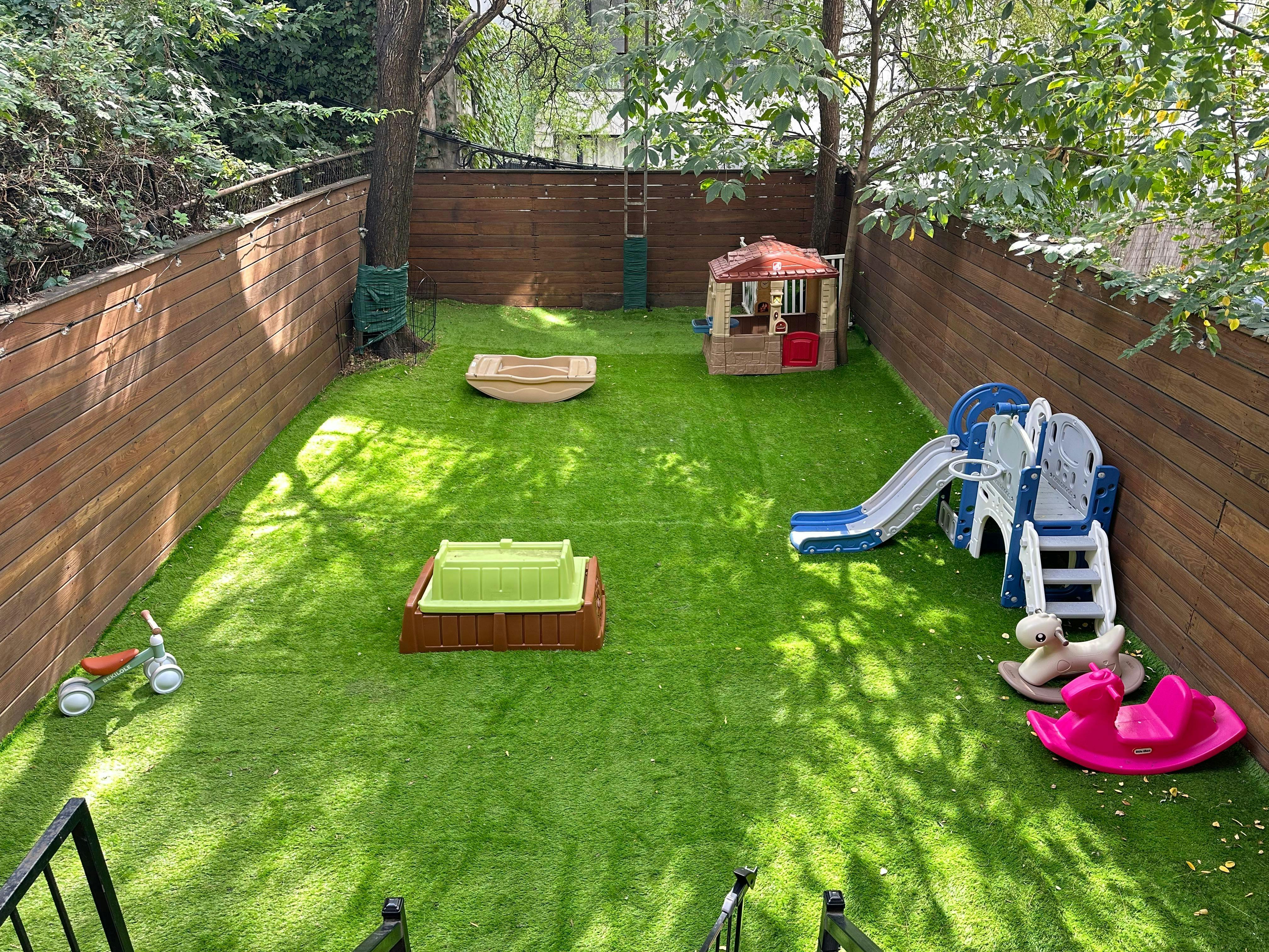 Backyard playground with artificial turf, slide, playhouse, and sandbox