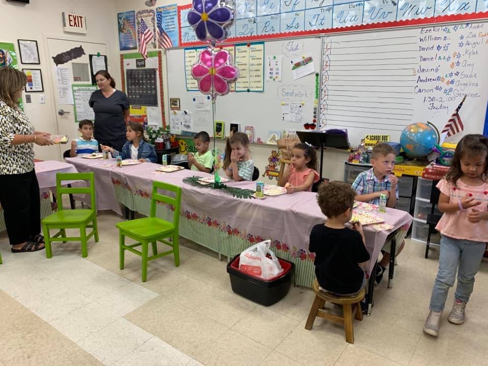 Adults and children in a classroom with children seated at tables
