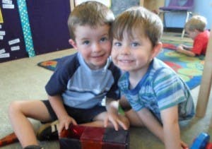 Two children sitting on the floor in a classroom