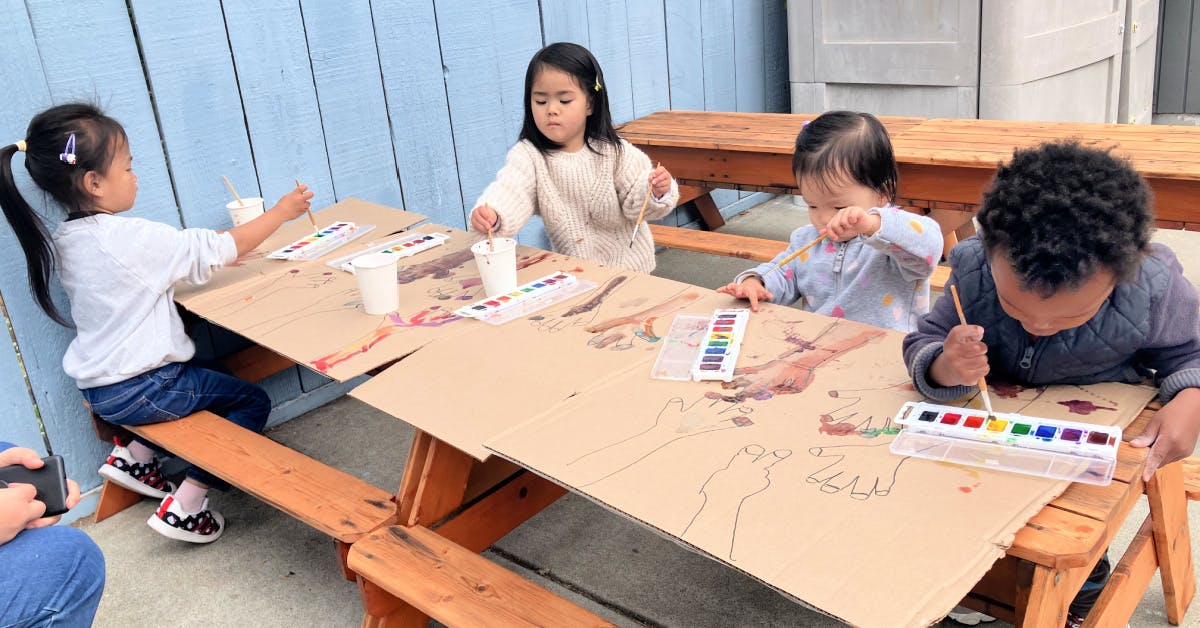 Children painting at a picnic table
