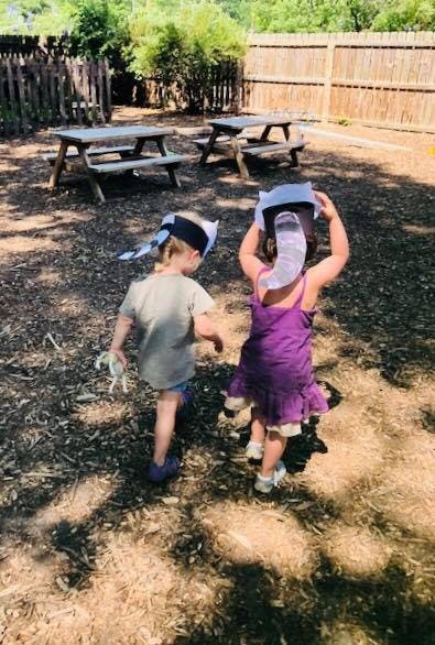 Two children walking away from the camera in an outdoor area