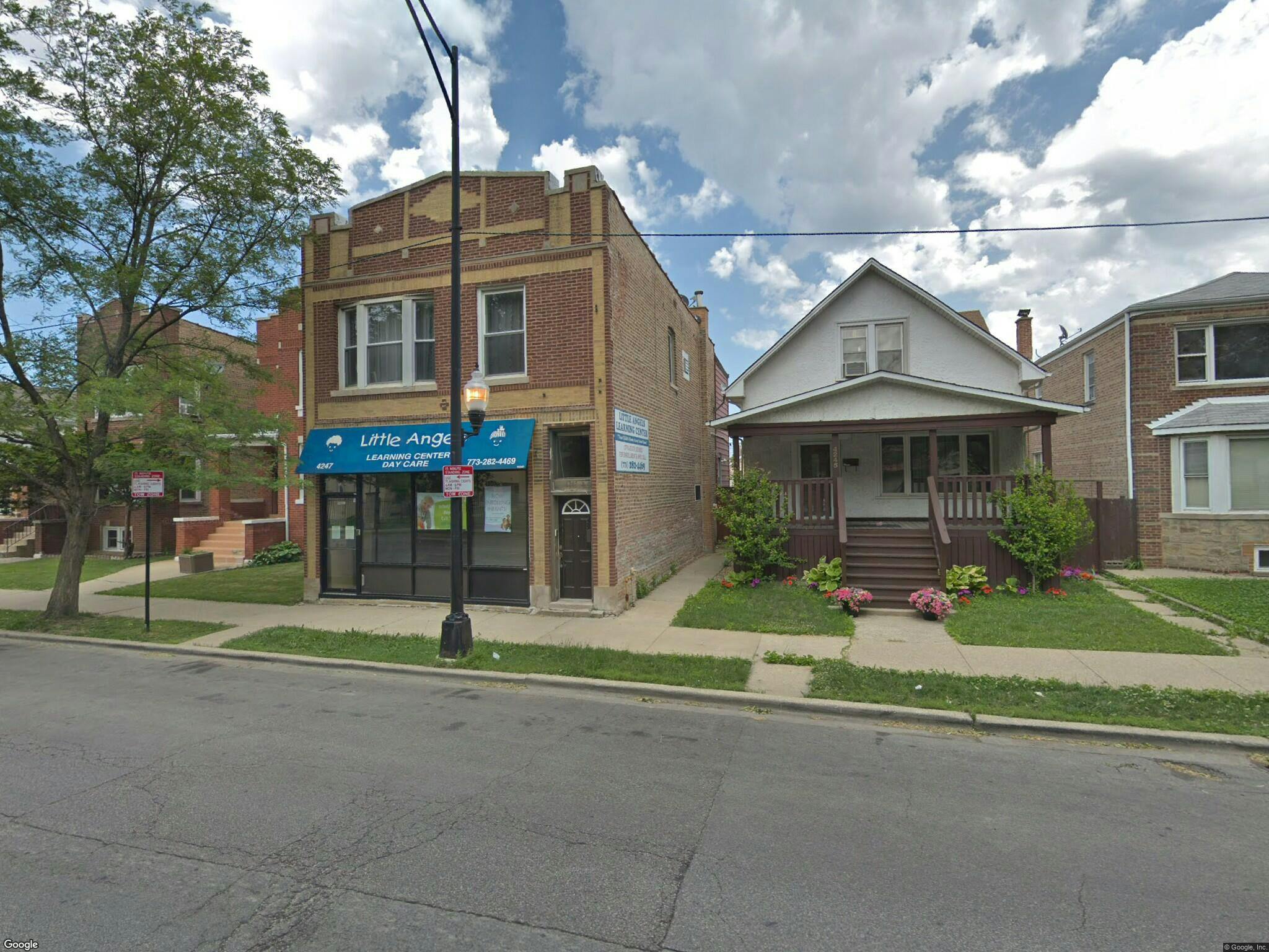 Street view of a brick building with a blue awning next to a white house