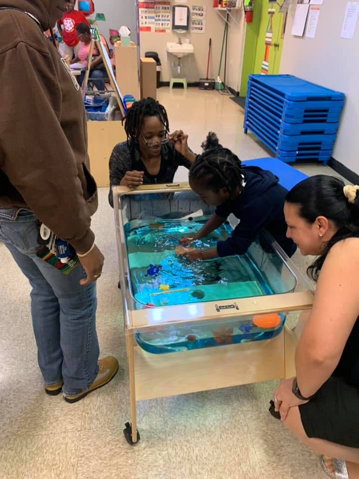 Adults and a child playing with a water table