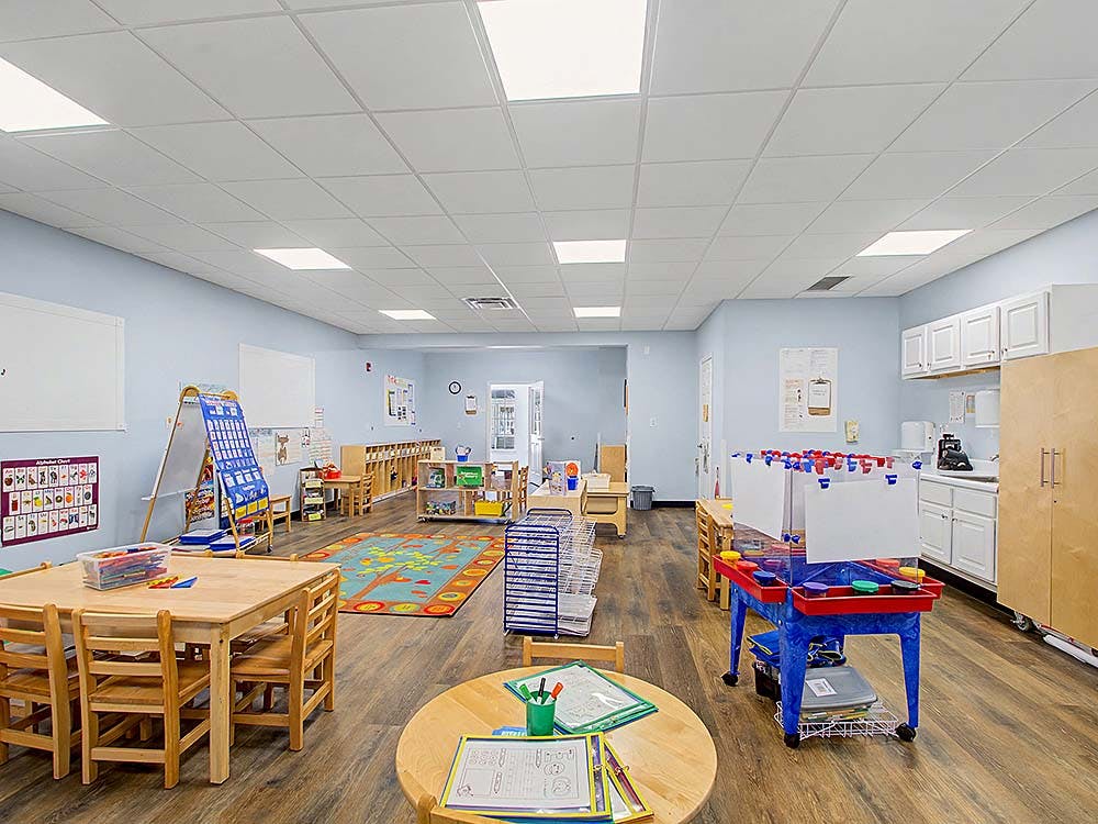Empty classroom with small wooden tables and chairs, and a sensory table
