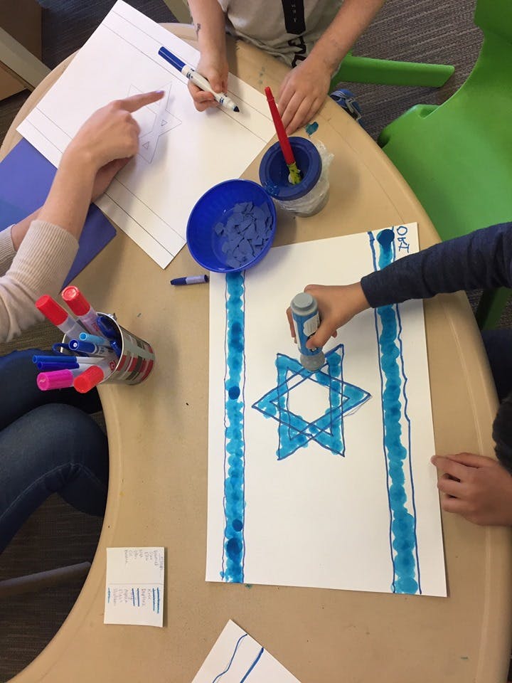 People making art with markers and paint, one drawing a Star of David