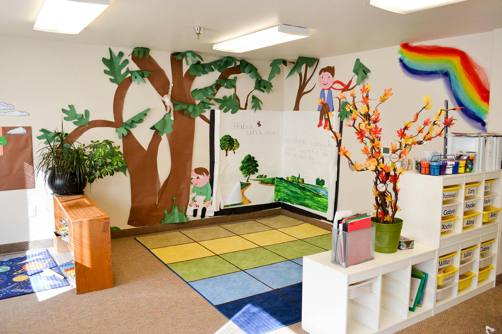 Classroom with tree mural, rainbow, and colorful rug