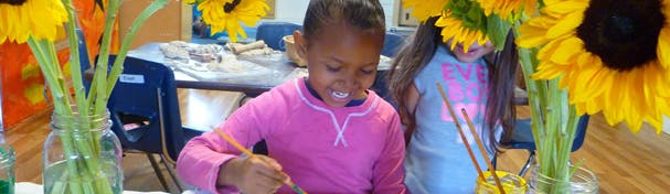 Child painting at a table with sunflowers