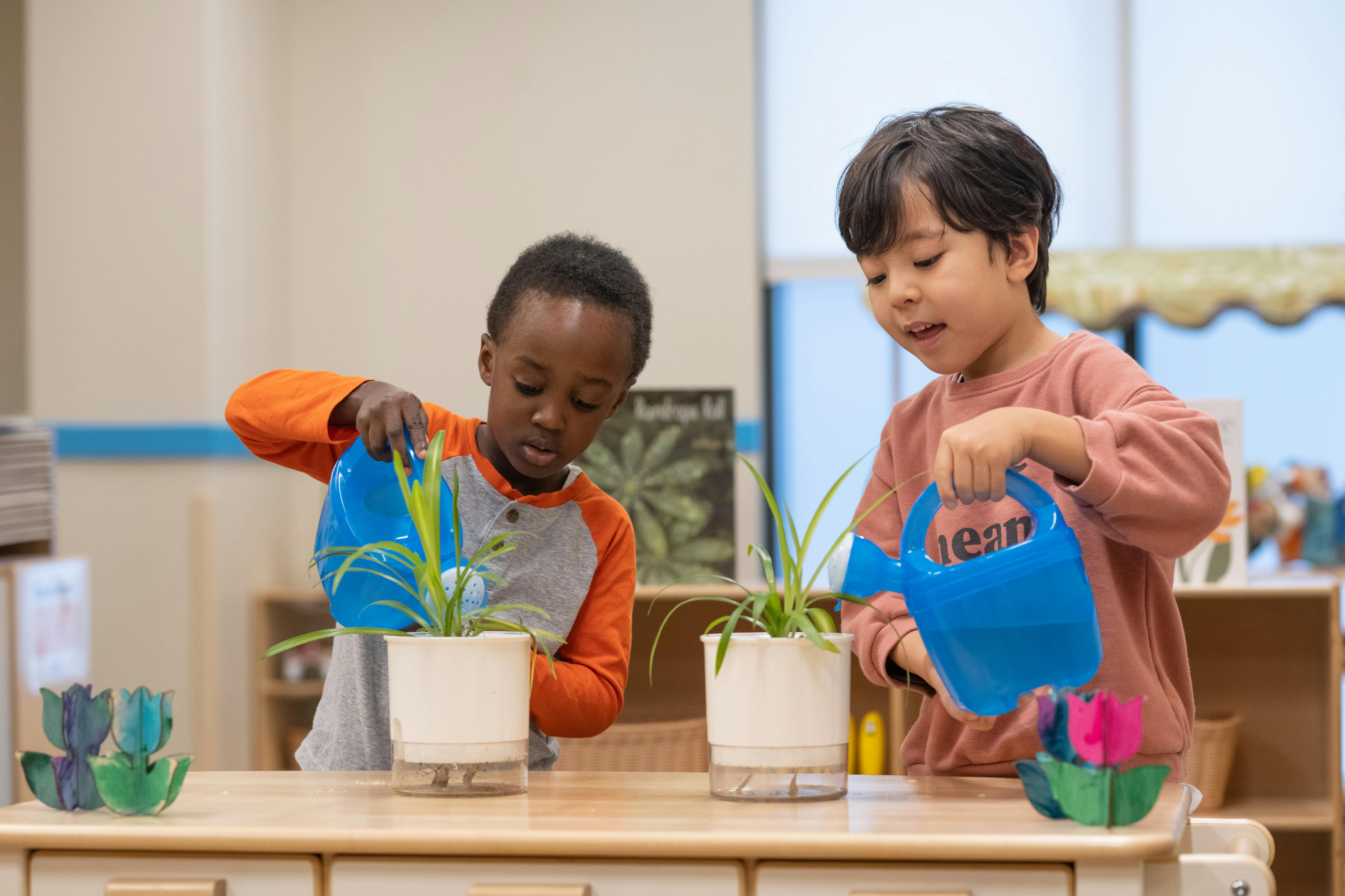 Two children watering plants with small watering cans