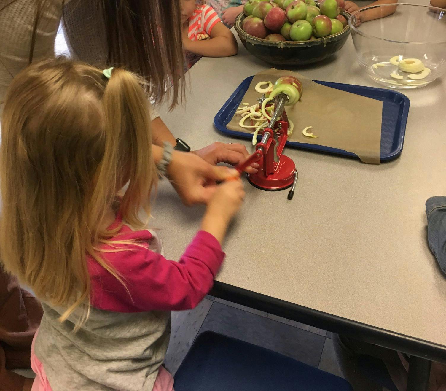 Child and person using an apple peeler