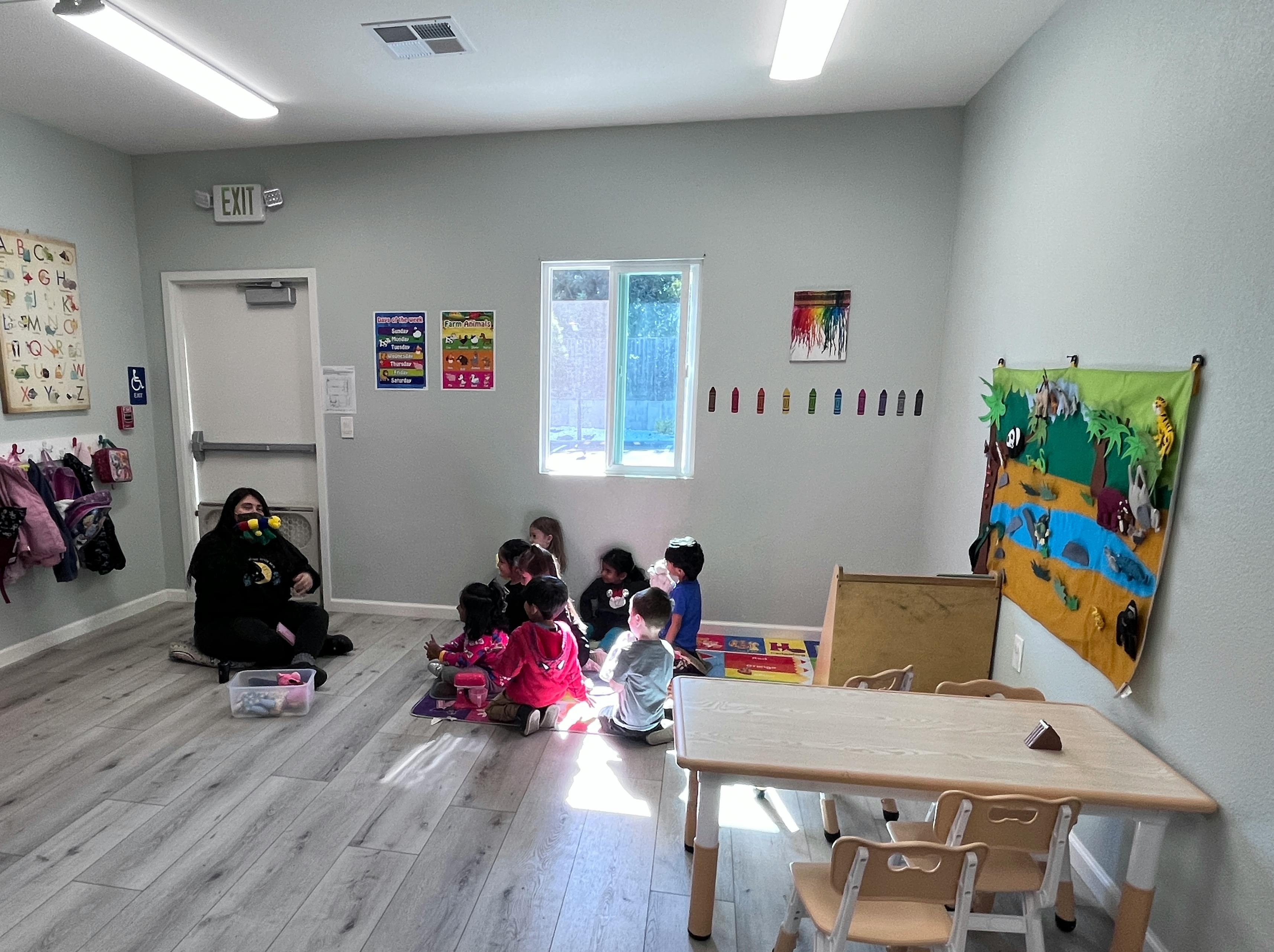 Adult and children sitting on the floor in a classroom