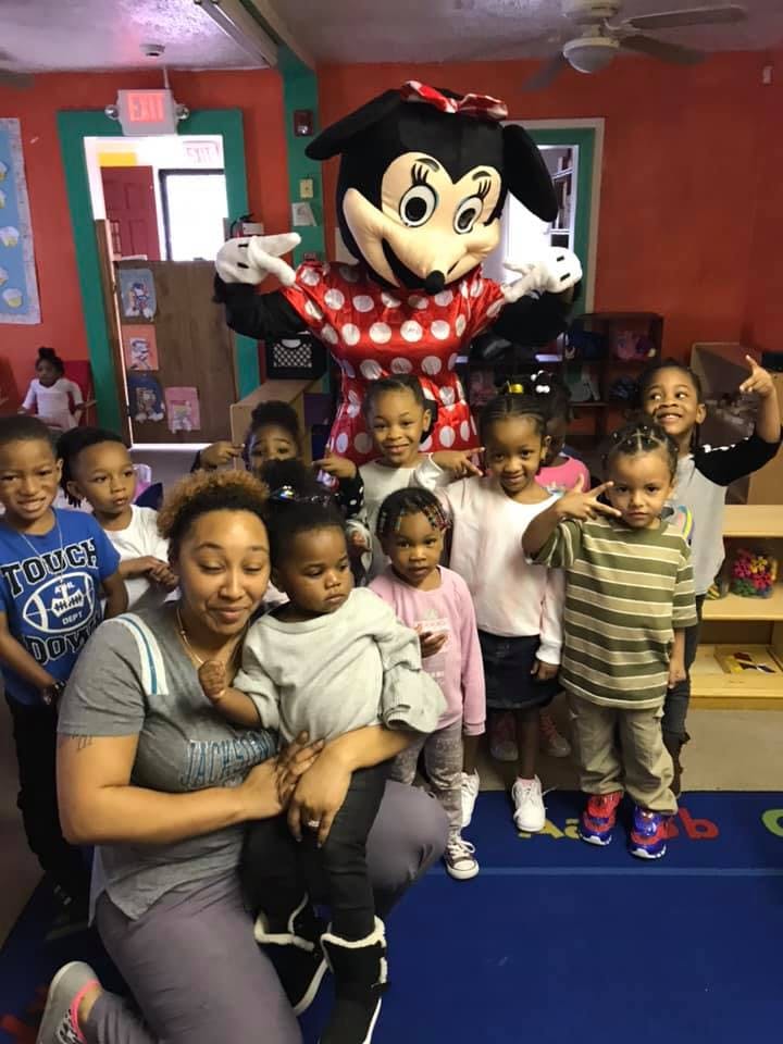Person in Minnie Mouse costume with a group of children and an adult