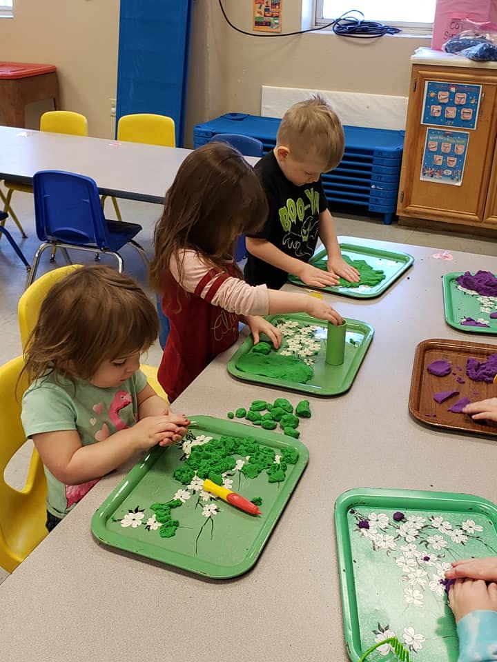 Three children playing with modeling clay at a table