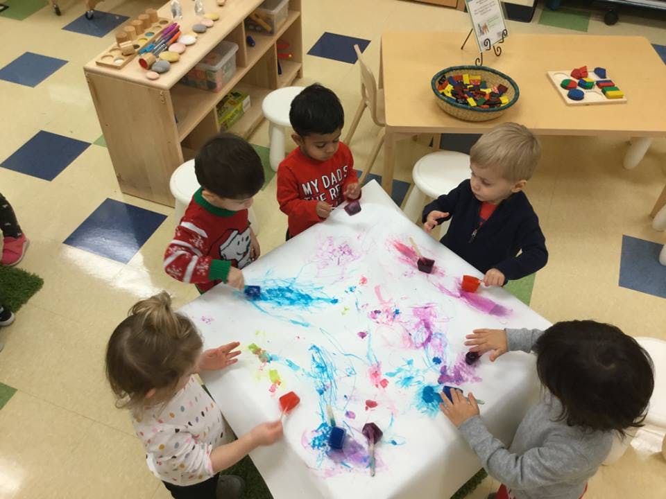 Children painting on a large sheet of paper on a table