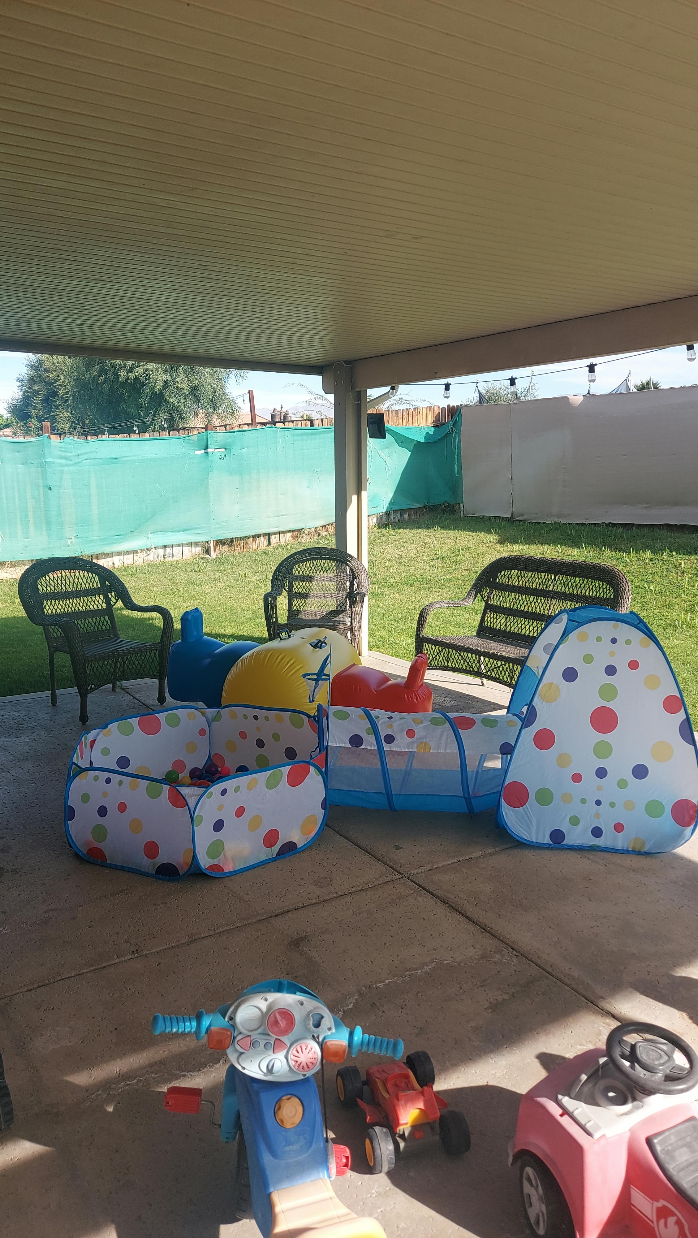 Children's outdoor toys on a patio including a play tunnel and ride-on toys