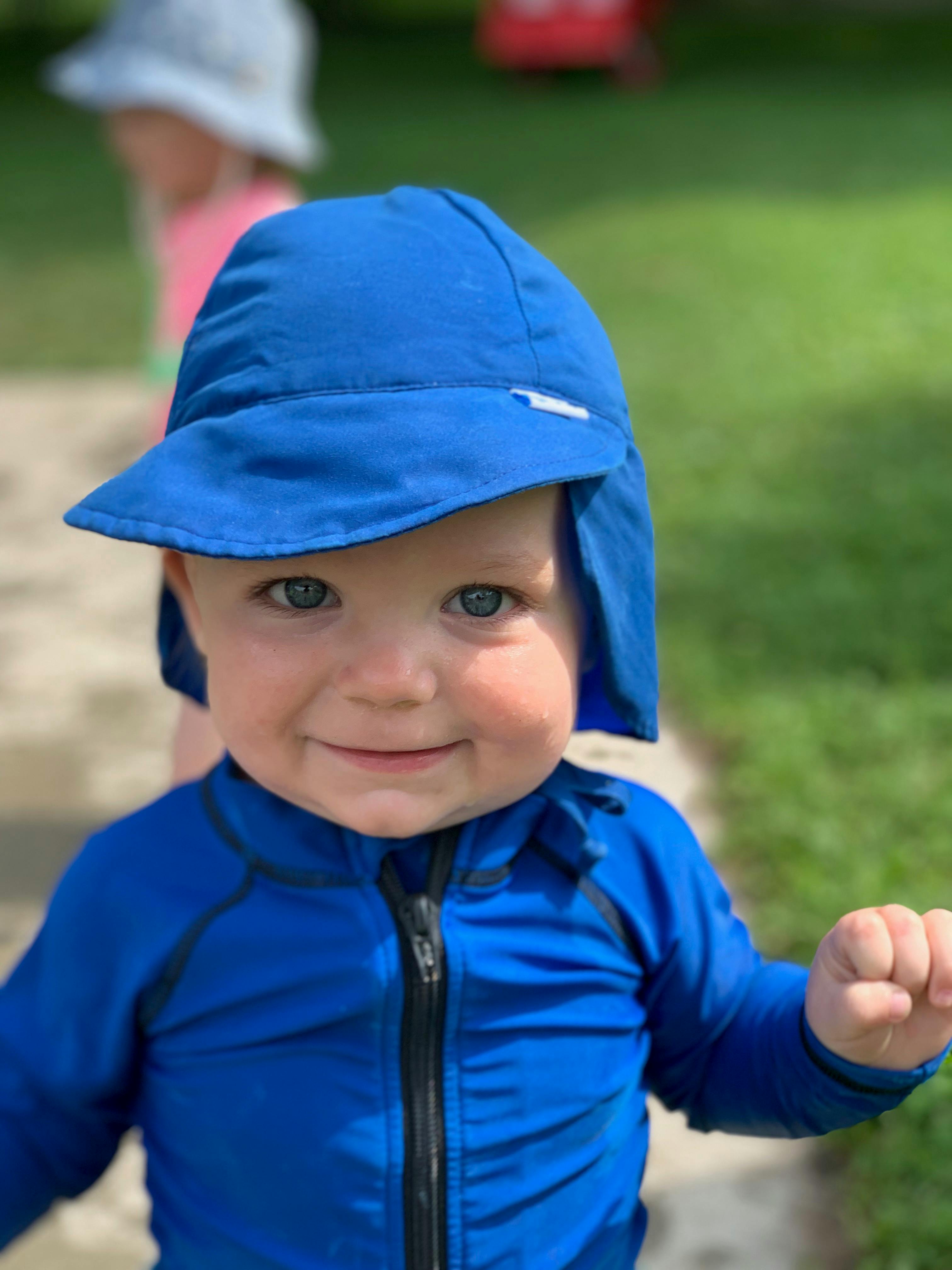 Child in blue sun hat and blue long-sleeved shirt
