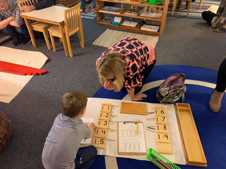 Adult and child on floor with number blocks and clipboard