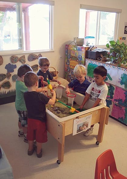 Children playing at a water table in a classroom
