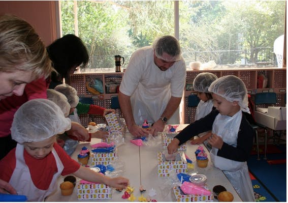 Adults and children decorating cupcakes at a table