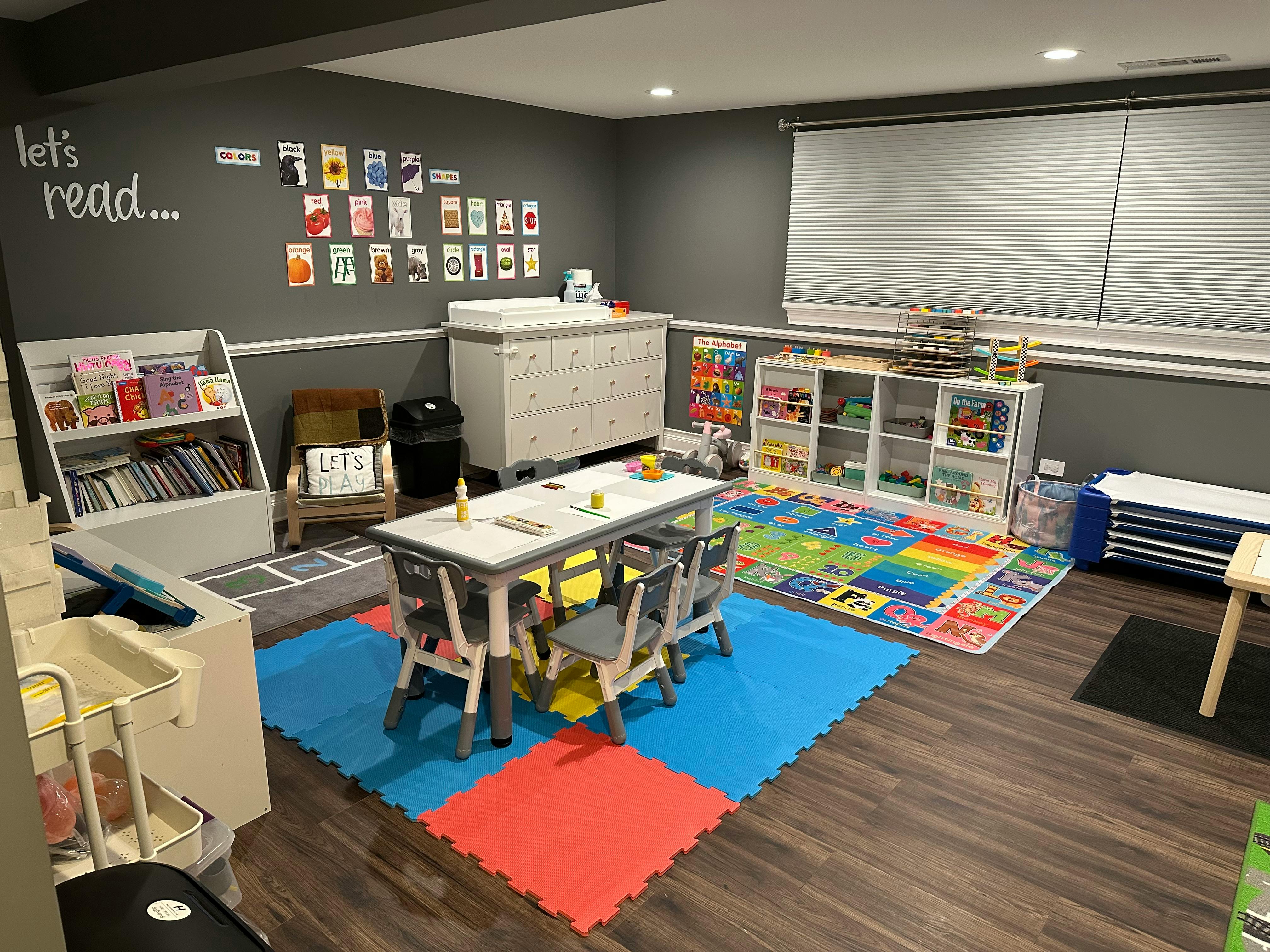 Children's playroom with a table and chairs, bookshelves, and play mats