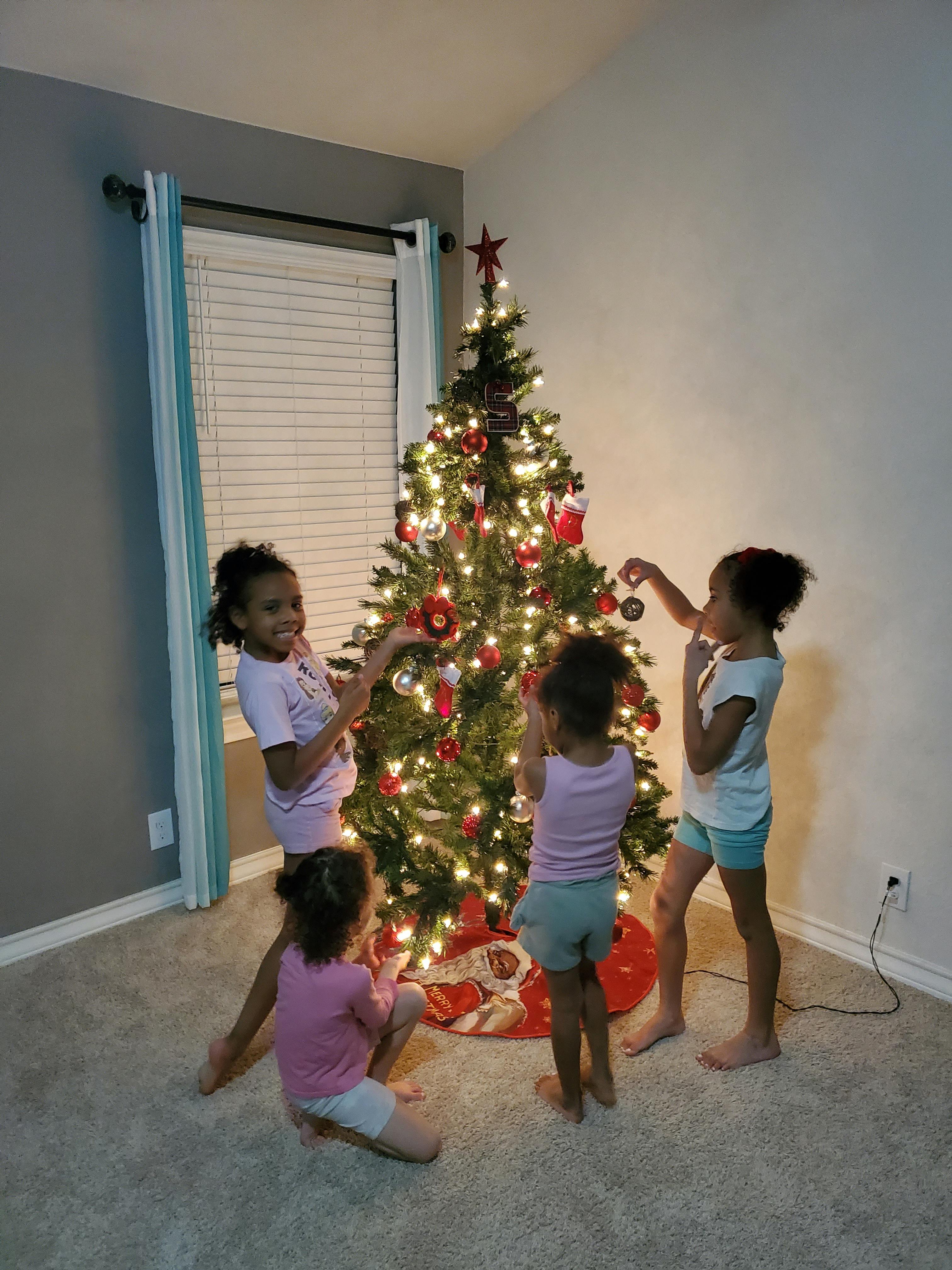Four children decorating a Christmas tree