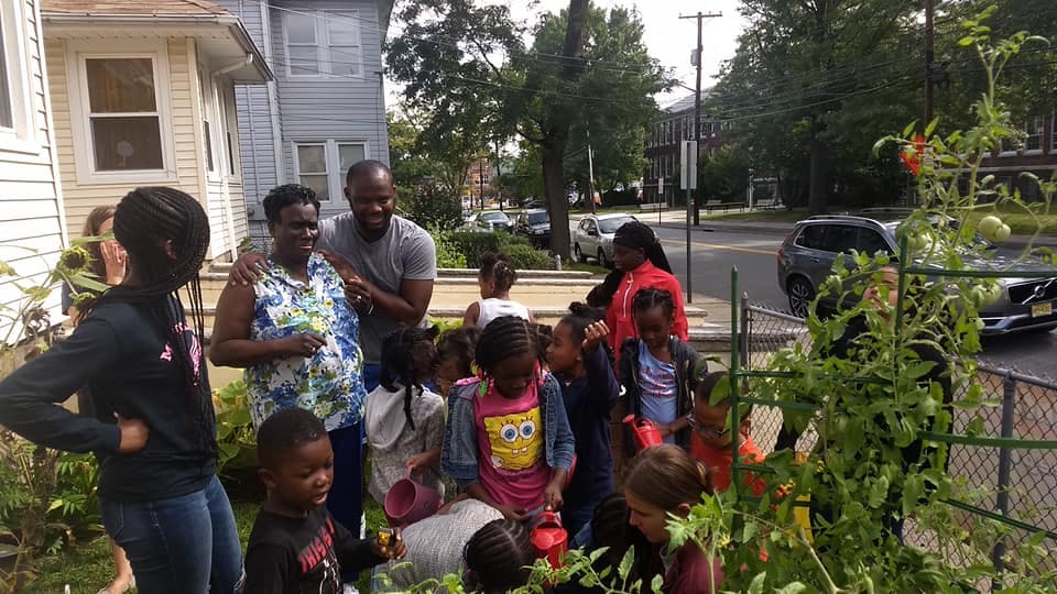 Adults and children gathered around plants in a garden