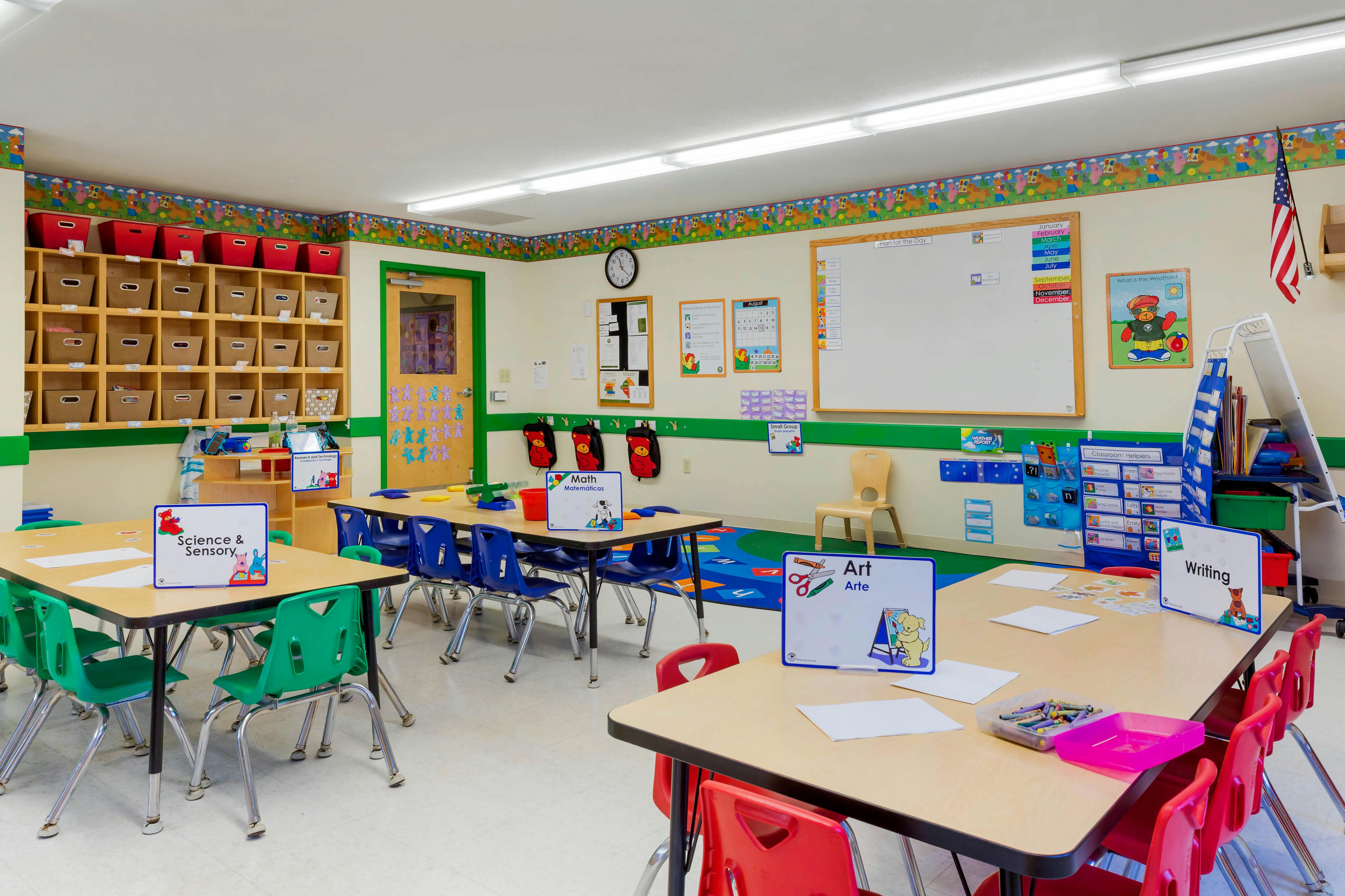 Empty classroom with small tables and chairs, educational posters on the walls