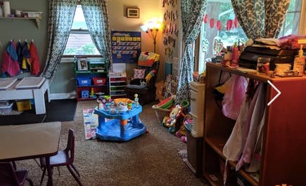 Playroom with child's activity center, small table and chairs, and toys