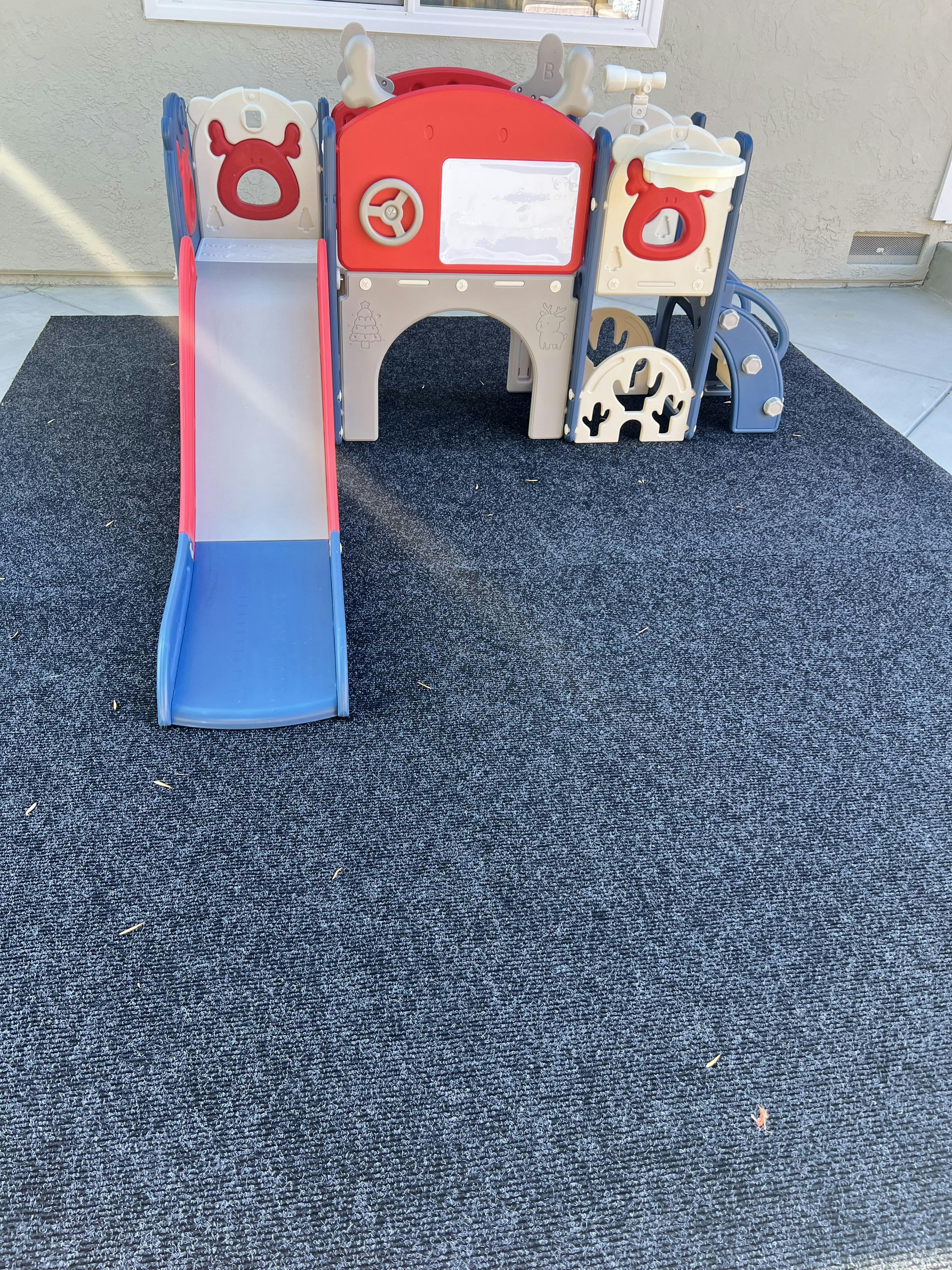 Plastic toddler playground structure with a slide on a carpeted mat