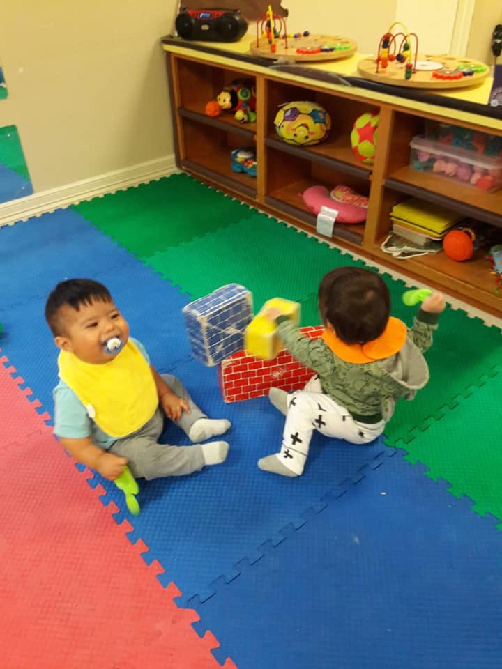 Two children playing with blocks on a colorful mat
