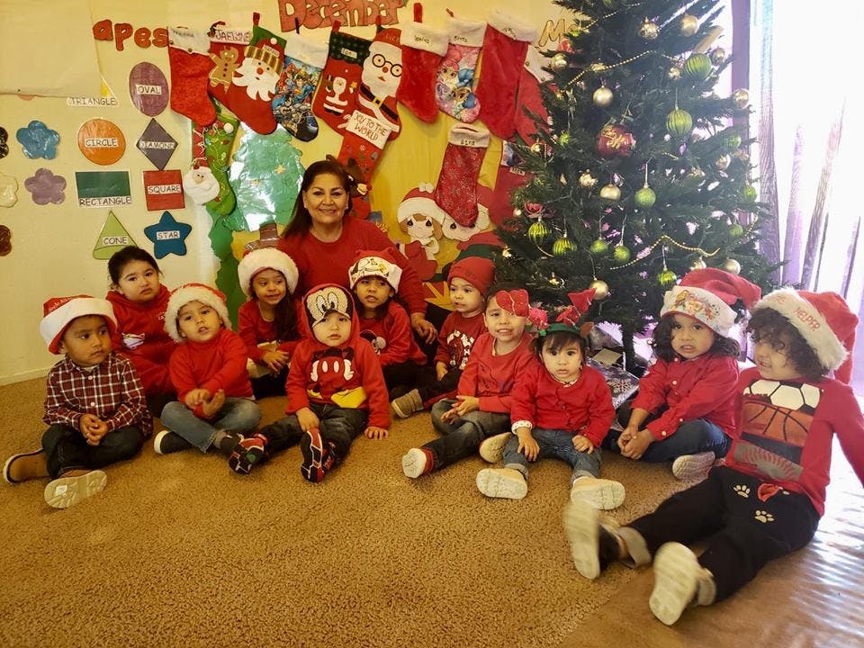 Adult and children in Santa hats sitting on floor near Christmas tree
