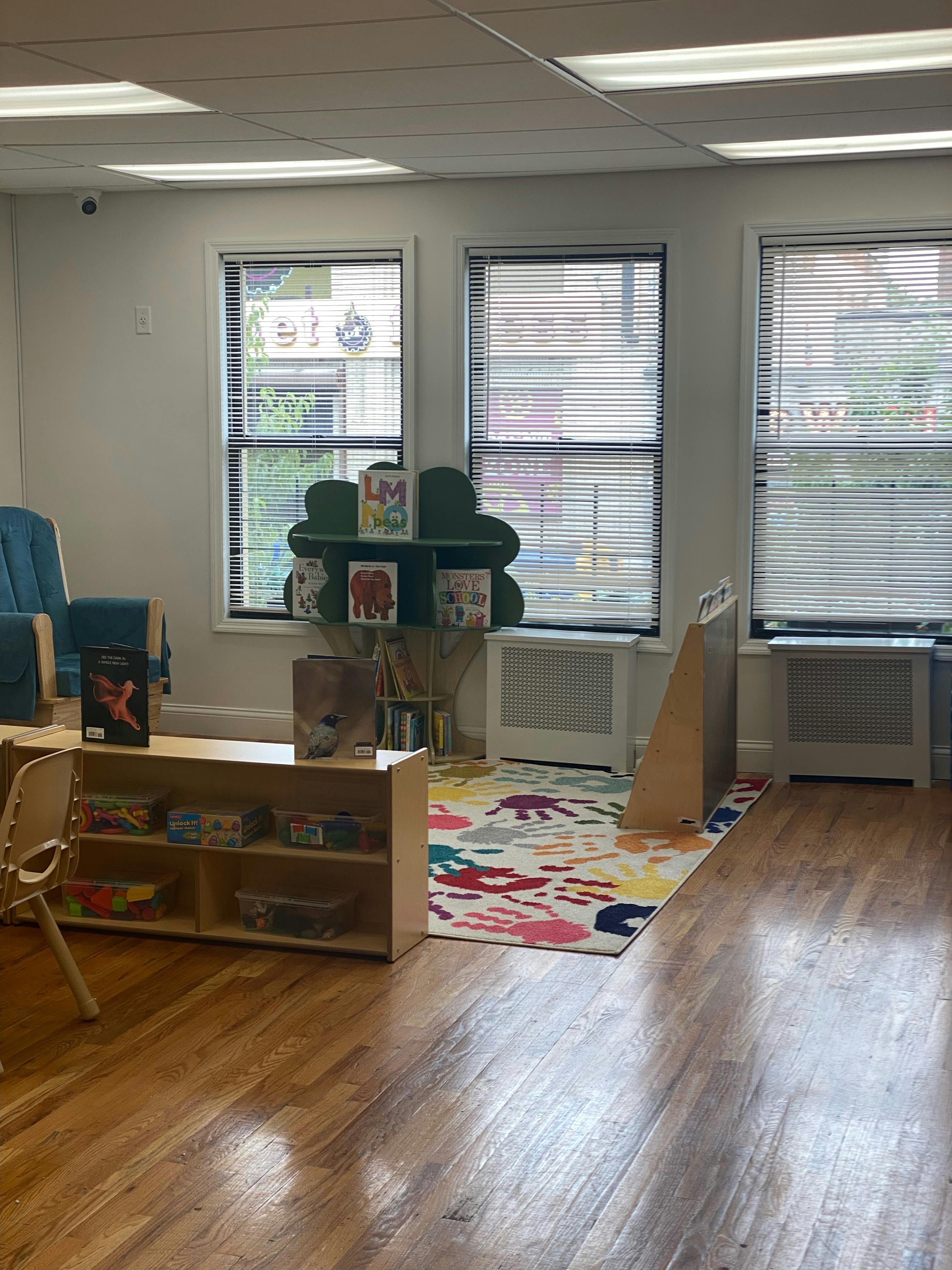 Classroom with a colorful rug, wooden shelves, and windows