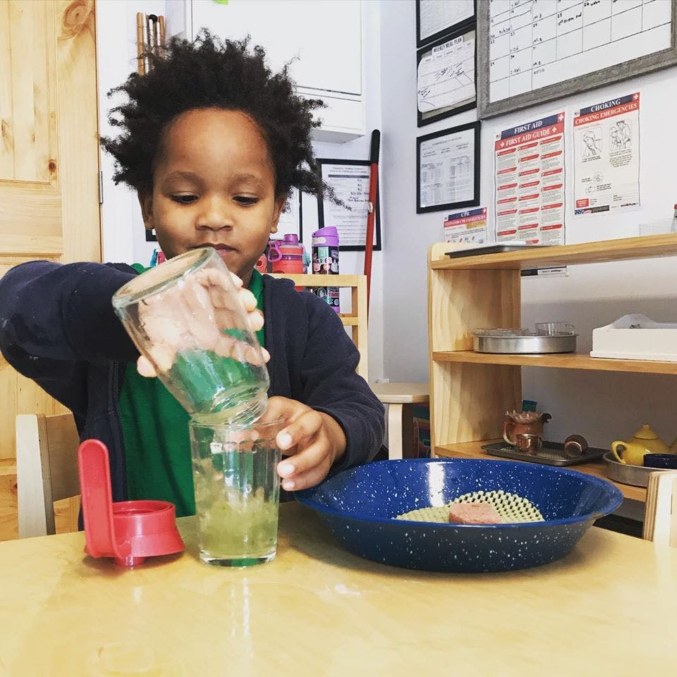 Child pouring liquid from one glass into another