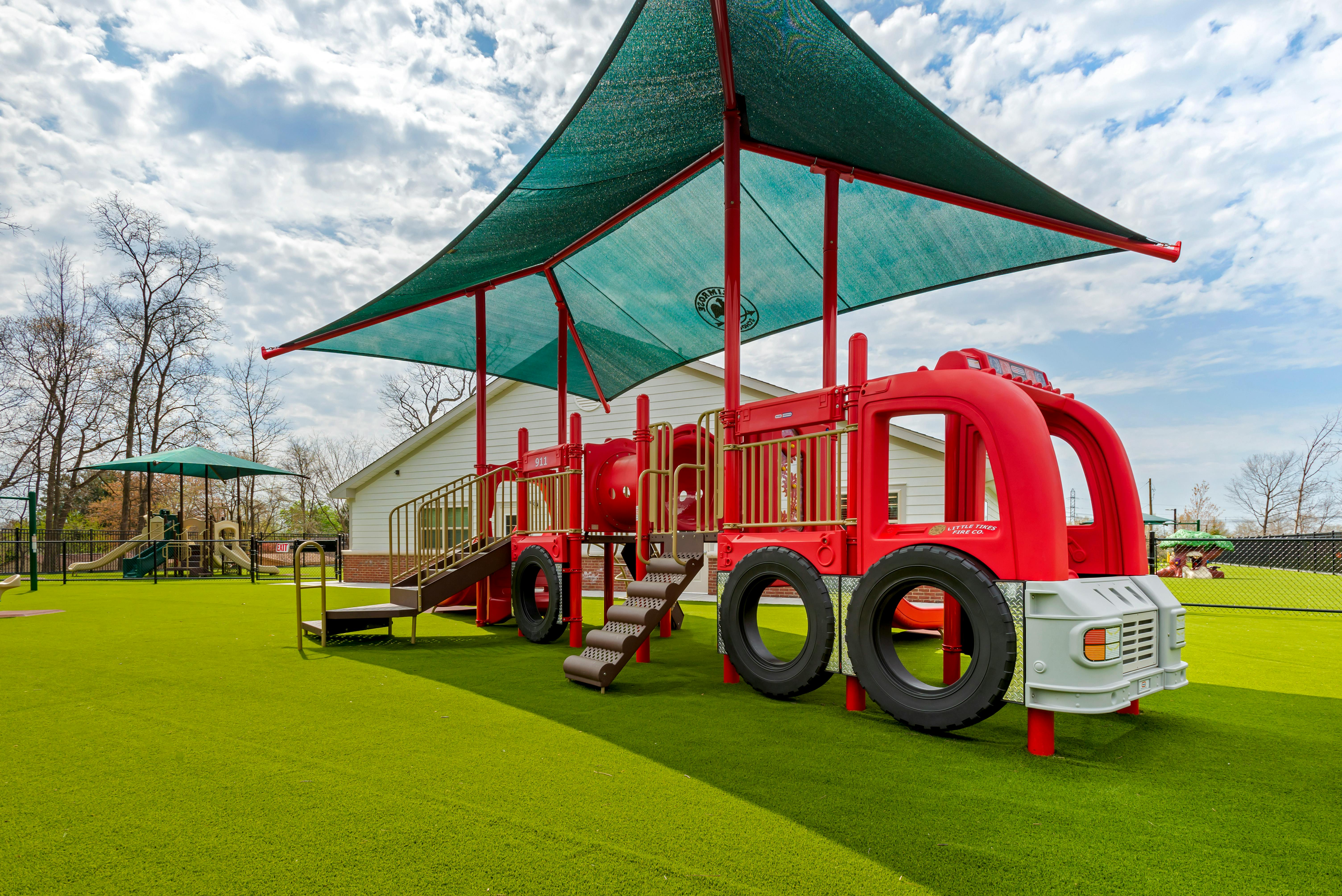 Red fire truck-shaped playground structure on green turf