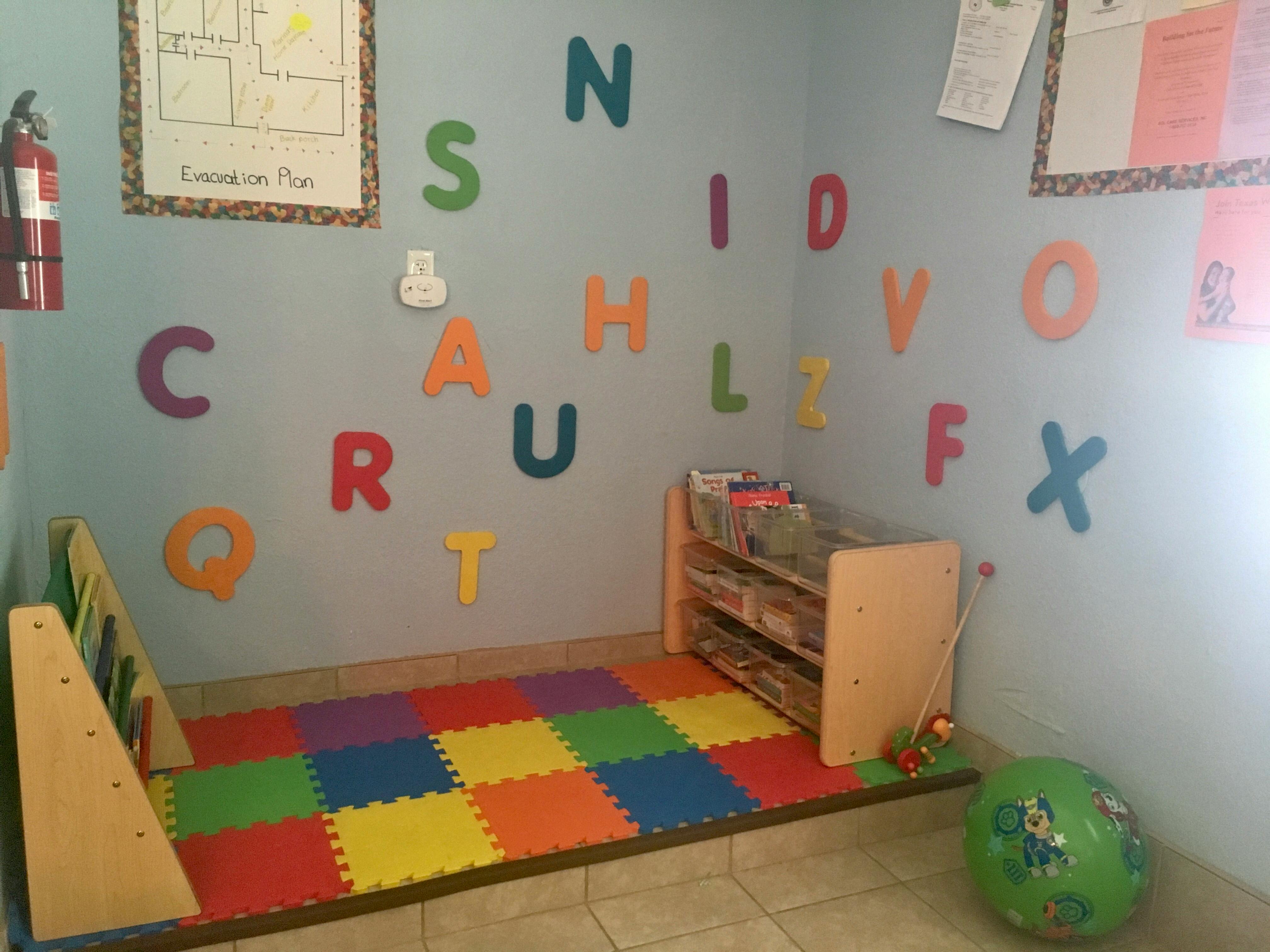 Classroom with colorful alphabet letters on the wall and a play mat on the floor