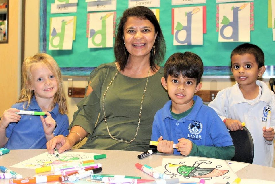 Person and three children coloring at a table in a classroom