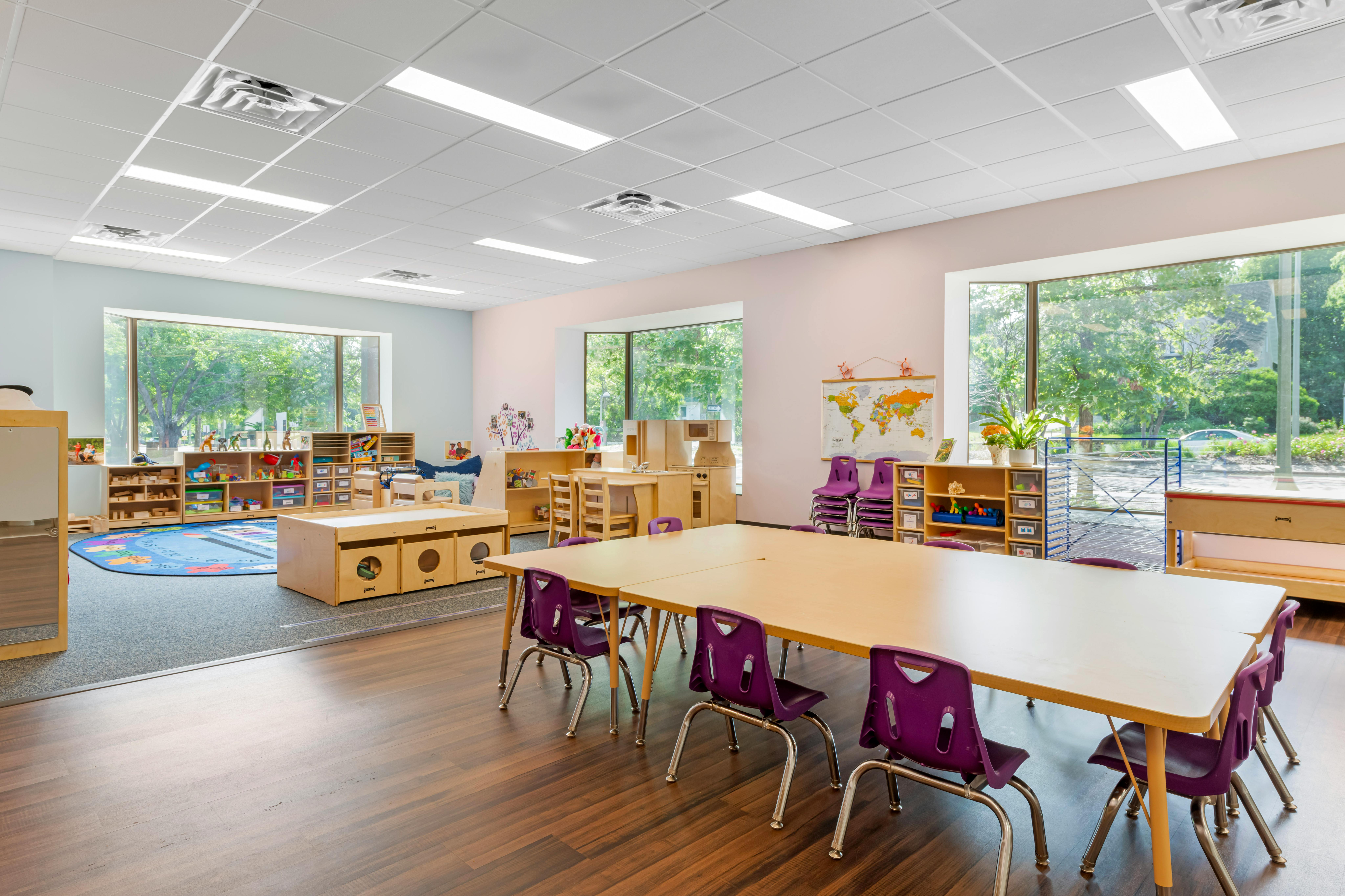 Empty classroom with tables, purple chairs, and play areas