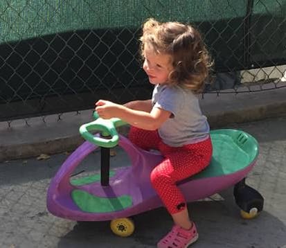 Child riding a purple and green toy
