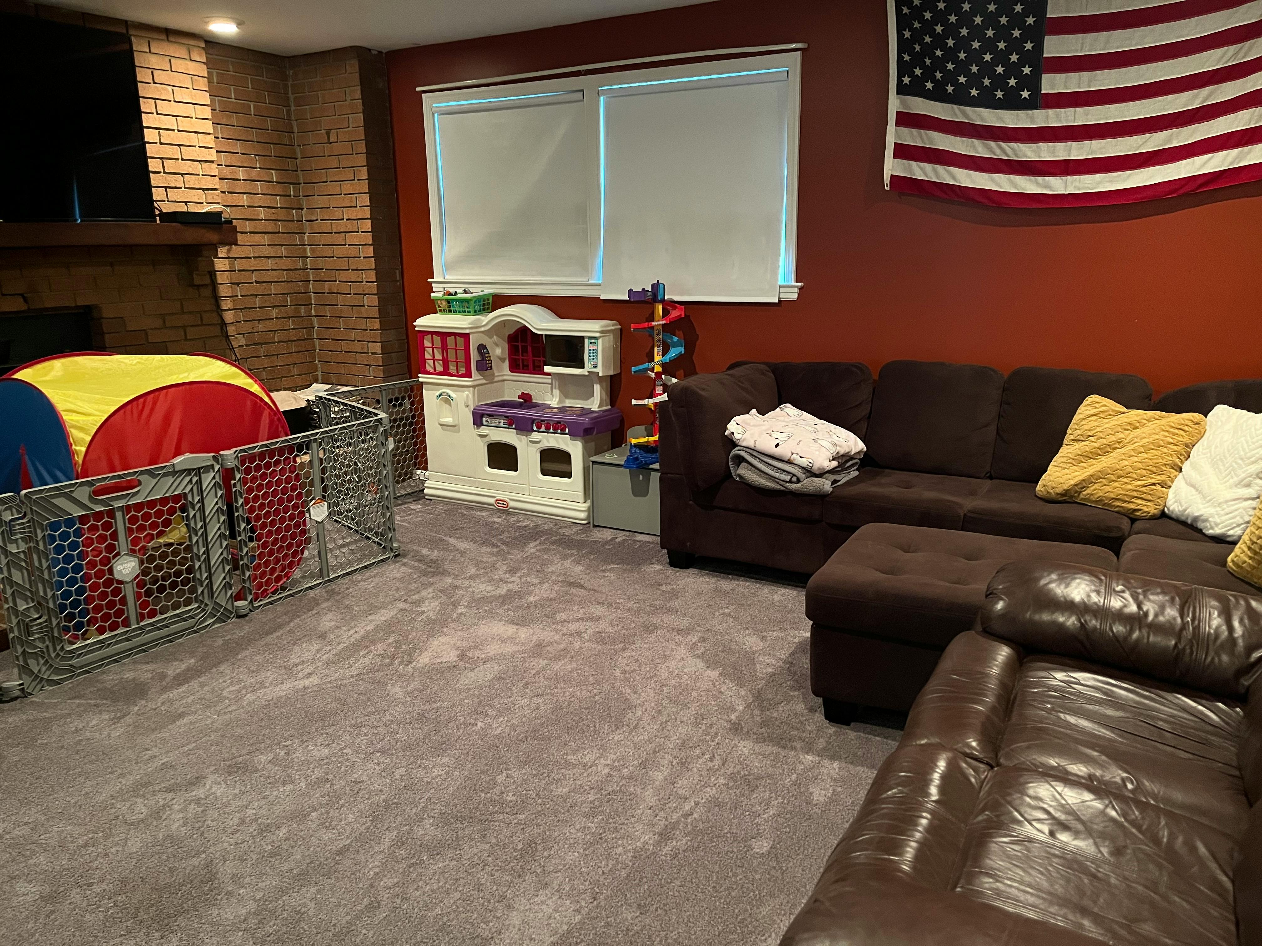 Living room with a playpen, toy kitchen, and sofas