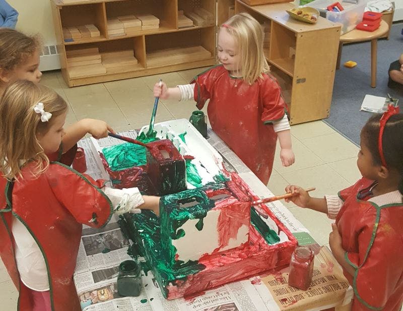 Children painting boxes in a classroom