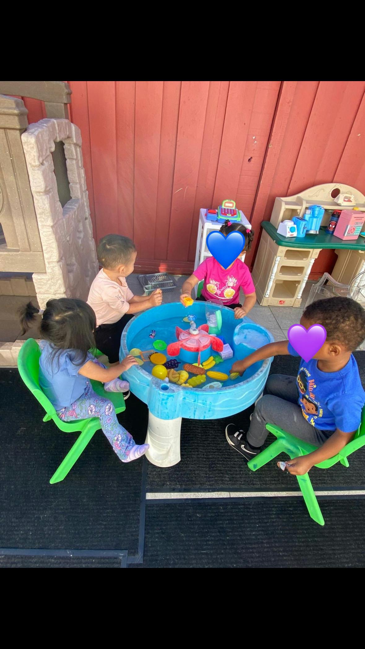 Four children playing around a water table with toys