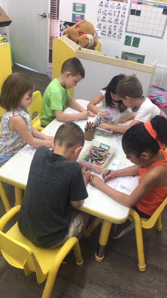 Children coloring at a table in a classroom